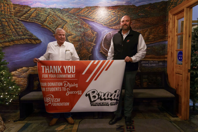 Brady Trucking owner, Larry Brady (left) and UBTech President, Aaron Weight (right) display a banner celebrating Brady’s generous donation of two CDL trucks to Uintah Basin Technical College, providing students with hands-on training opportunities.