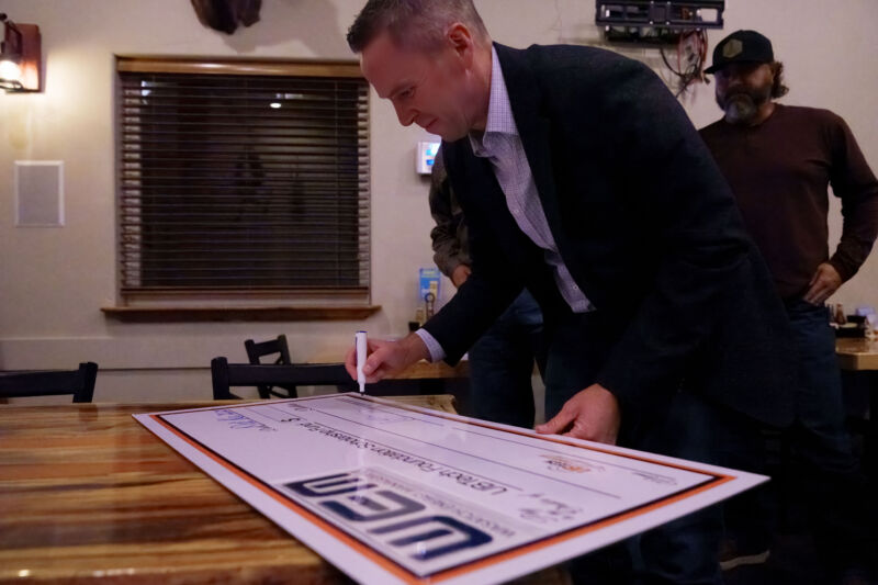 Kimball Hodges, President of Wasatch Energy Management/WEM Operating (WEM), signs a ceremonial check celebrating their scholarship contribution to UBTech students.