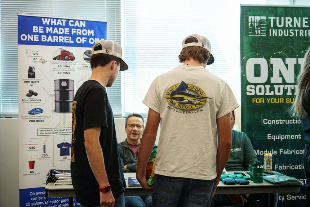 Two male students talking to an adult male about their company