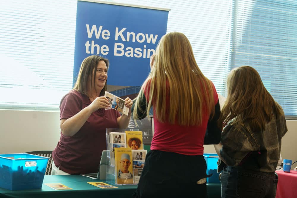 Two female students talking to an adult female about their company