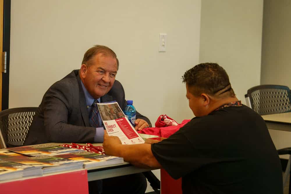 An adult male community member talking to another adult male about the company he is representing