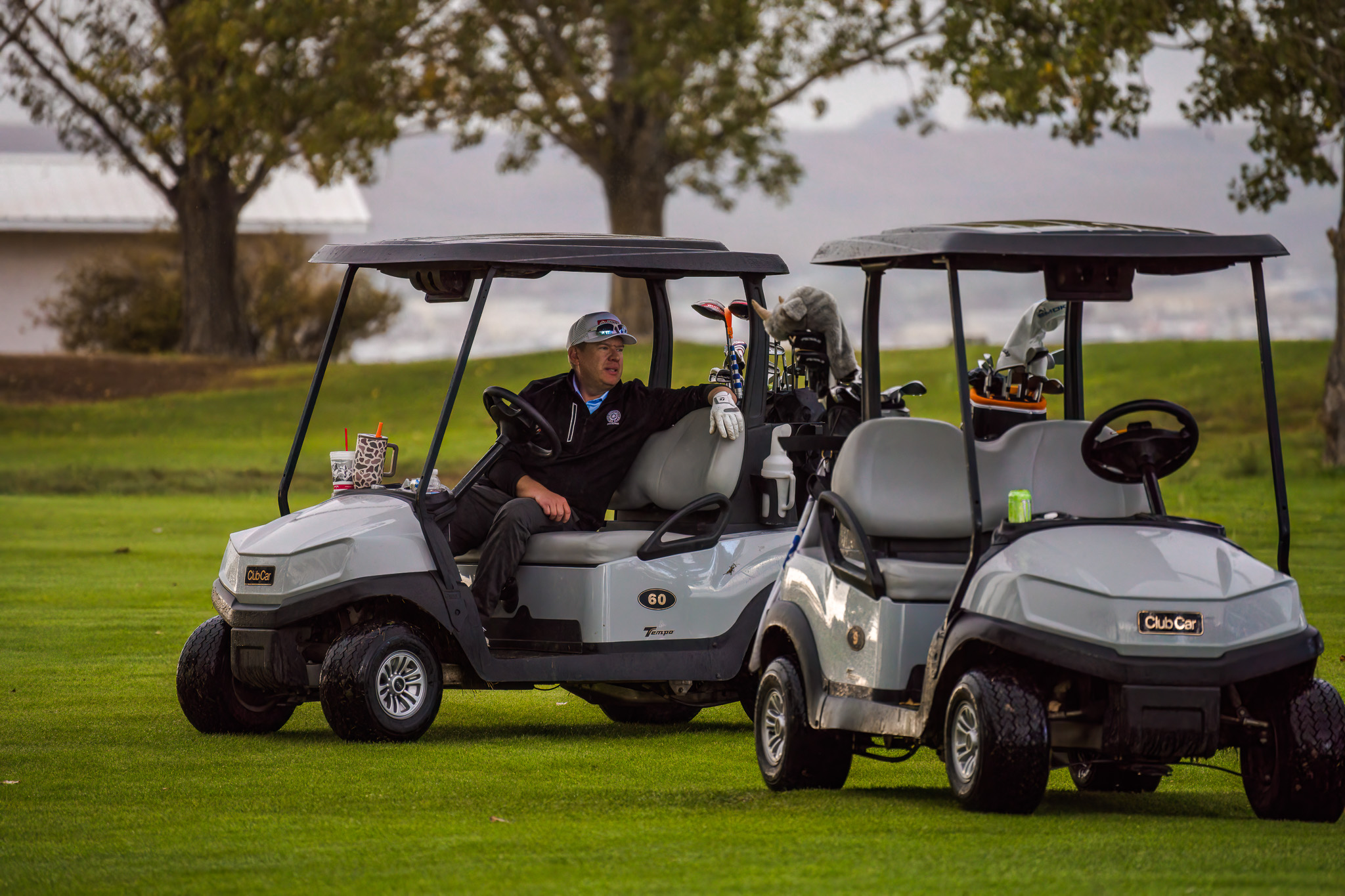 Two golf carts parked with a man sitting in one of the carts