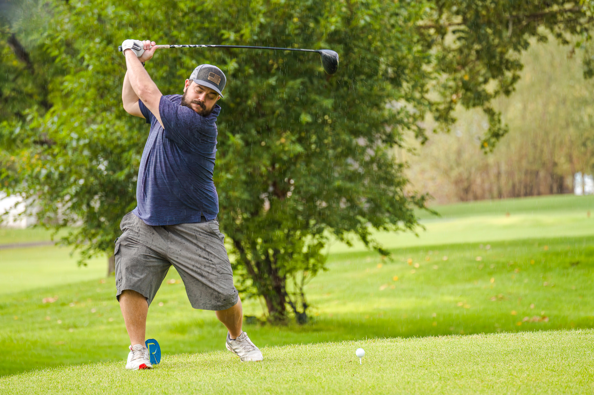 a man mid backswing in the rain