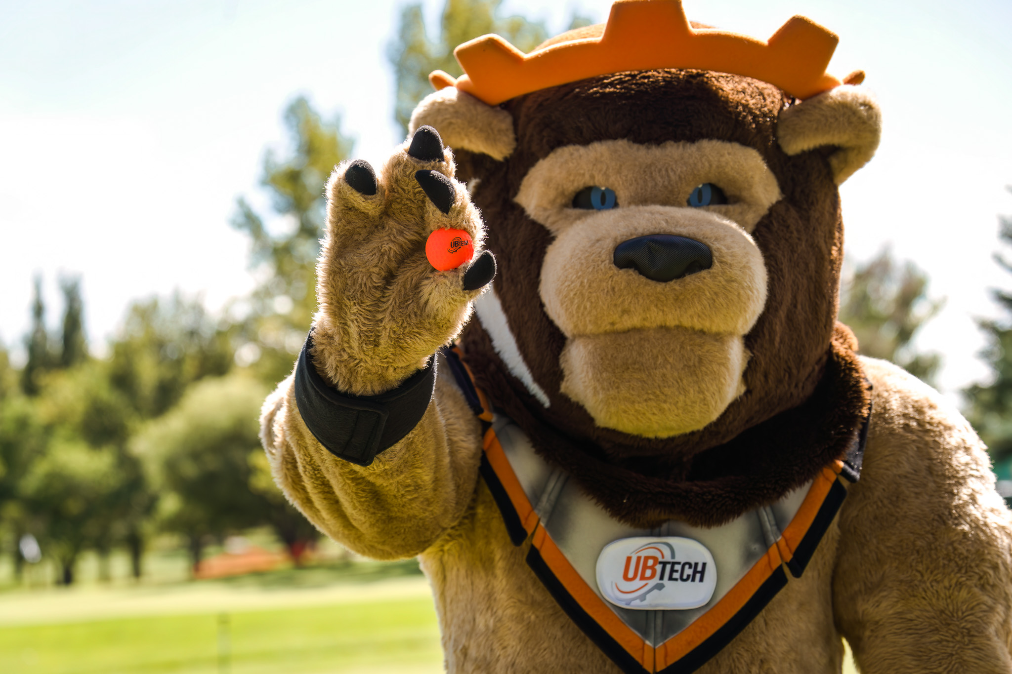 Lion mascot holding a golf ball that reads UBTech between his claws