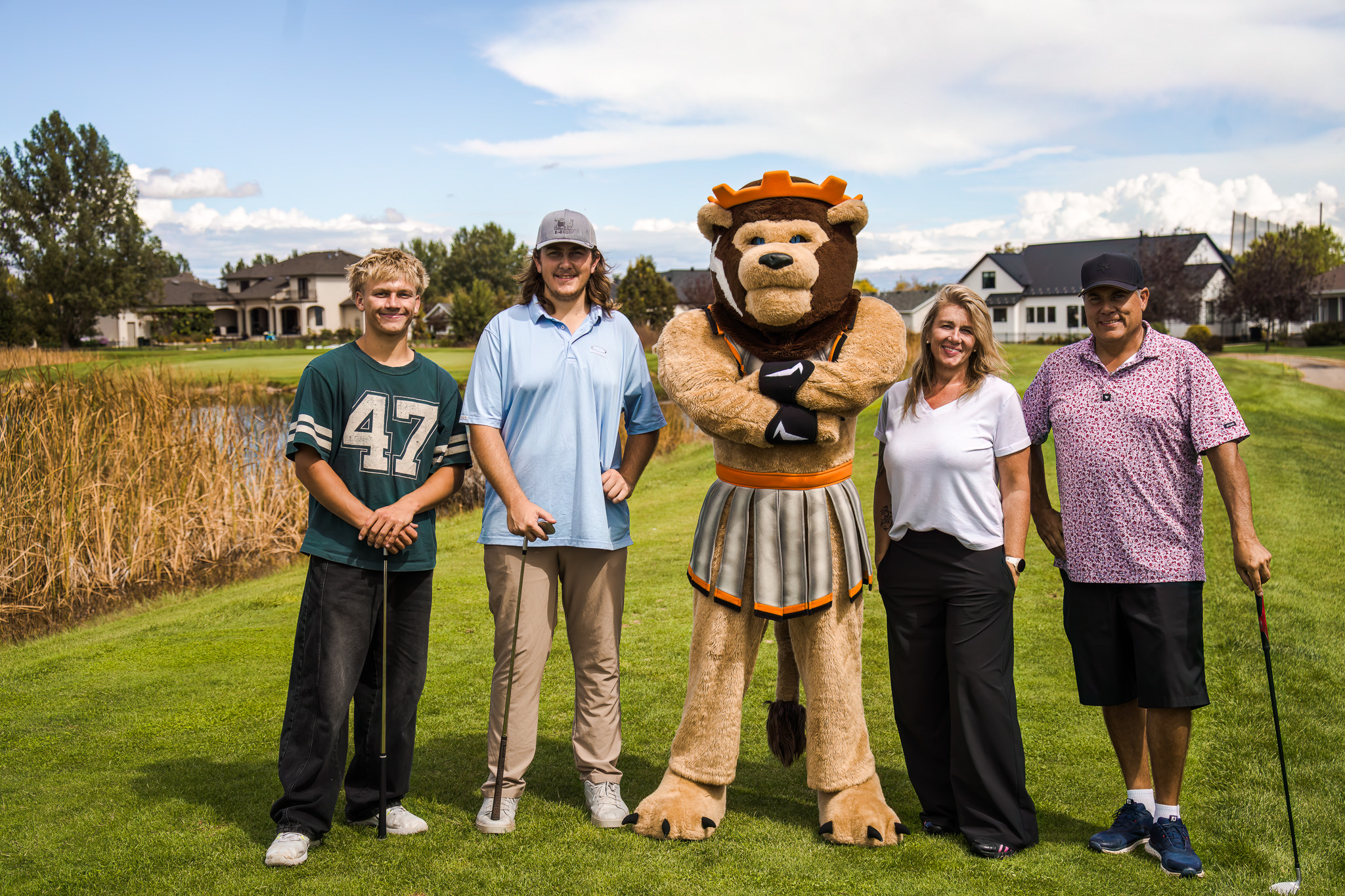 Three men and a woman posing with the lion mascot