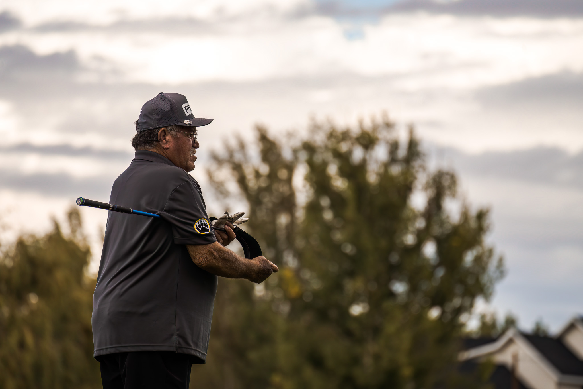 Older man taking off a golf club cover