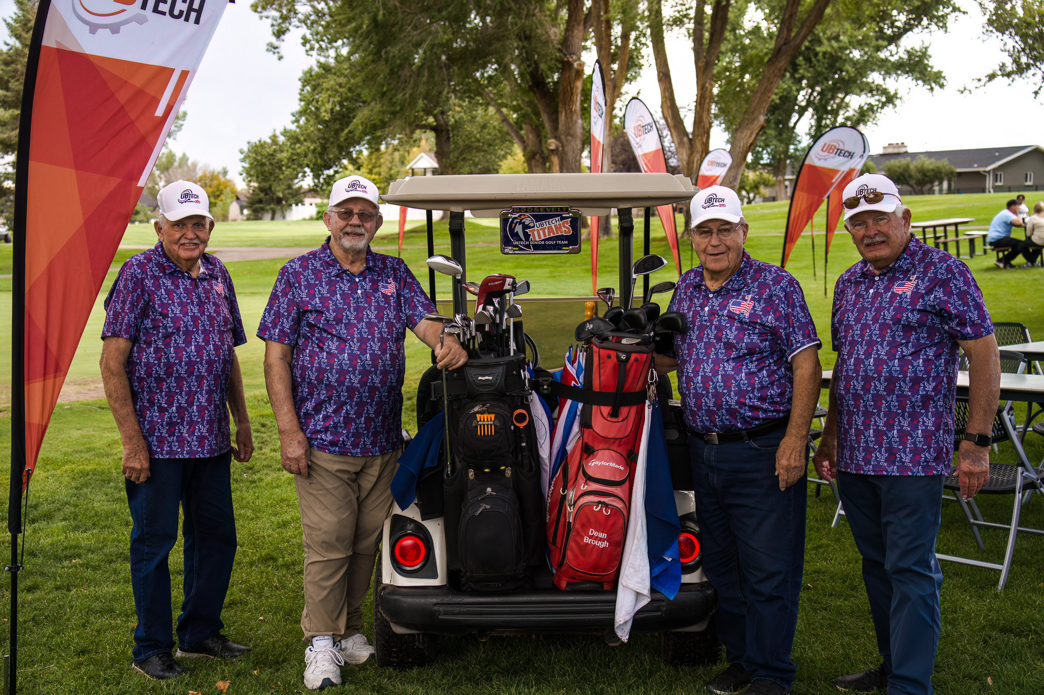 Four elderly men posing with a golf cart that has a UBTech license plate