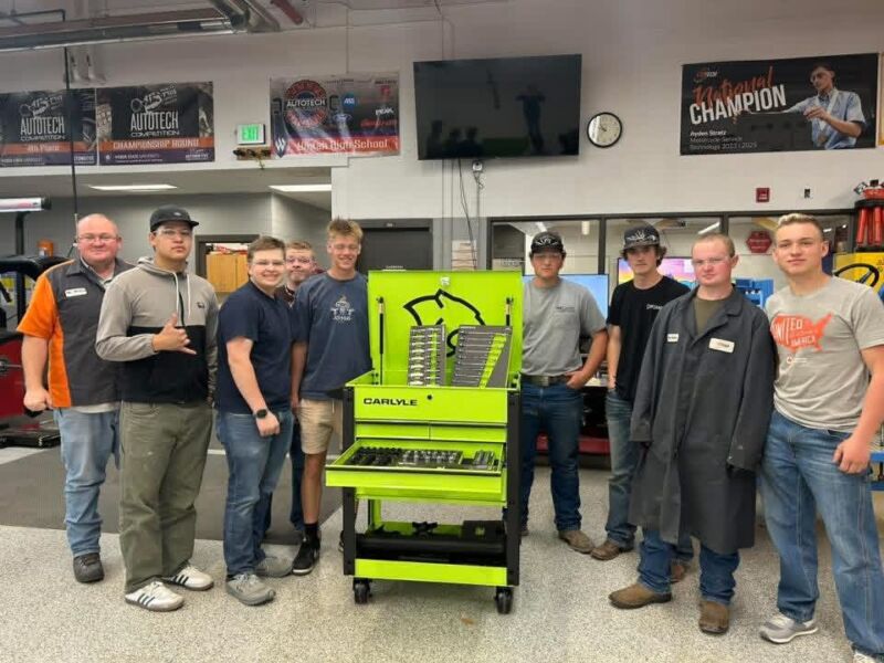 Eight students and a instructor surround the bright lime green Carlyle tool box posing for the photo.